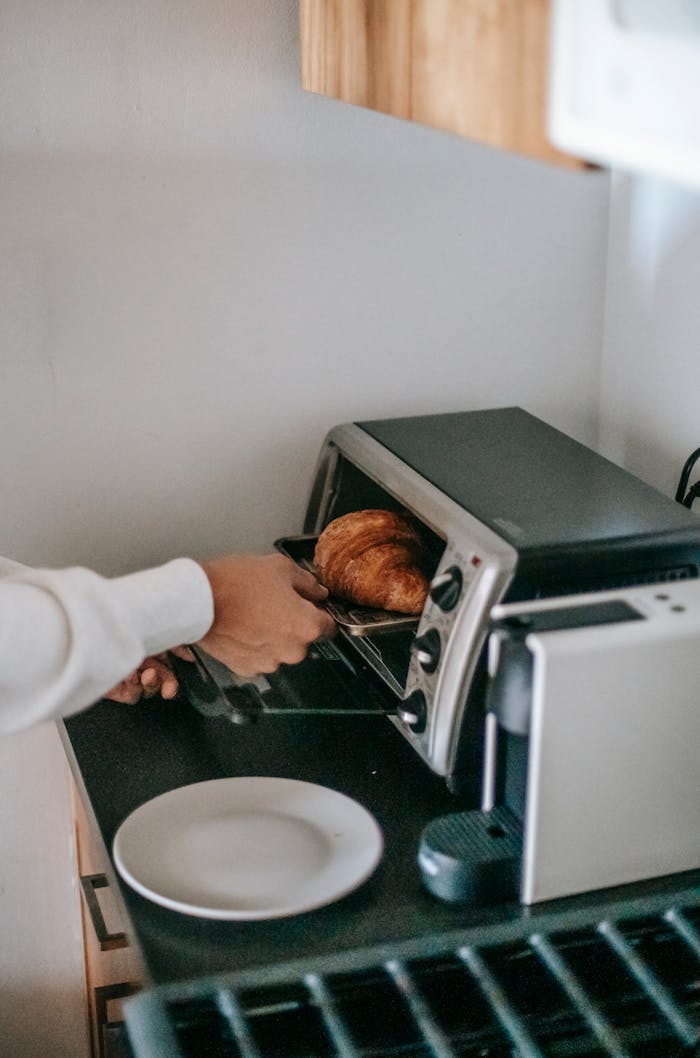 who-we-are From above of crop anonymous person using microwave oven while heating yummy croissant for breakfast